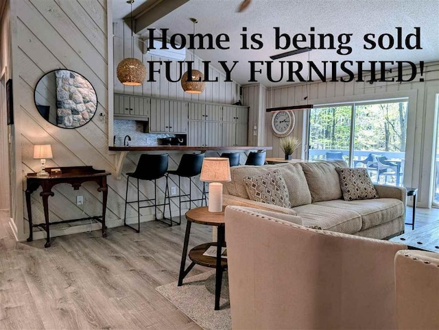 5350 Golfview Rd, Bellaire, MI 49615 - living room featuring wood walls, light wood-style flooring, and high vaulted ceiling
