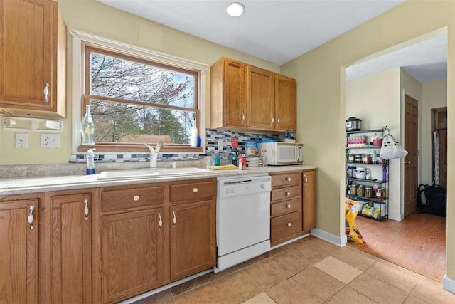 512 NW Kalkaska St, Kalkaska, MI 49646 - kitchen featuring white appliances, a sink, light countertops, brown cabinets, and decorative backsplash