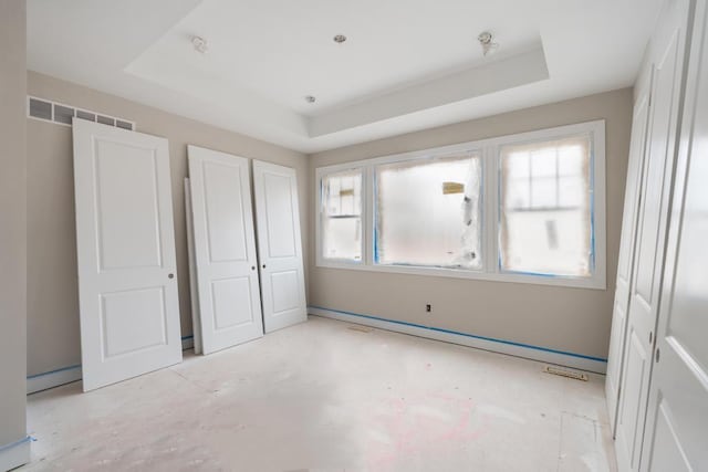 unfurnished bedroom featuring a raised ceiling and a closet
