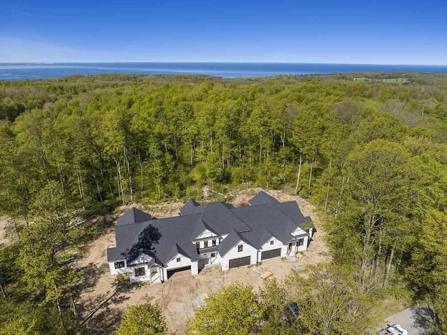 view from above of property featuring a heavily wooded area and a nearby body of water