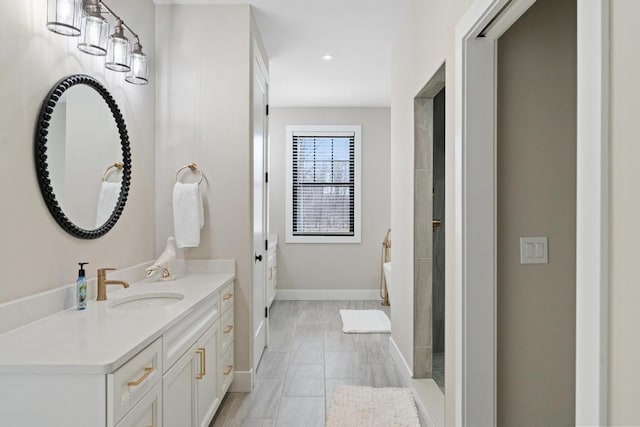 bathroom with vanity, baseboards, and a bath