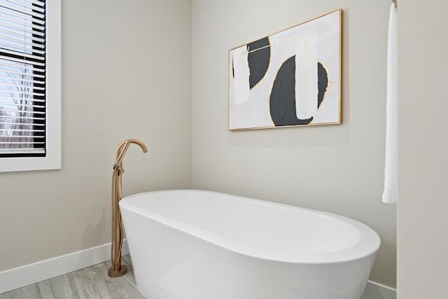 full bath featuring baseboards and a soaking tub