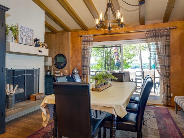 998 N Shr, Walloon Lake, MI 49796 - dining space with beamed ceiling, a chandelier, wood finished floors, wood walls, and a brick fireplace