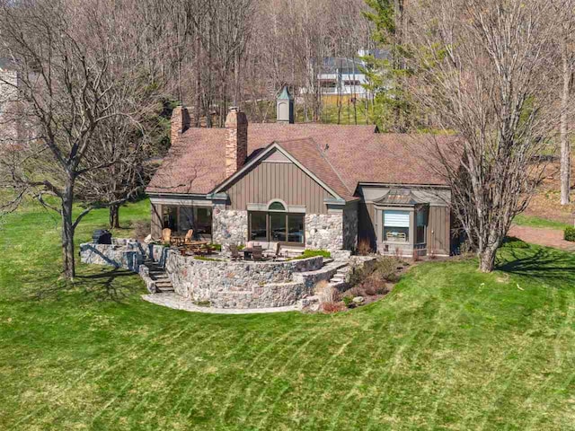 110 Birchwood Dr, Harbor Springs, MI 49740 - back of house featuring a chimney, a yard, board and batten siding, stone siding, and a patio area