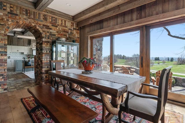 110 Birchwood Dr, Harbor Springs, MI 49740 - dining space with beam ceiling, arched walkways, dark wood-style floors, and wood walls
