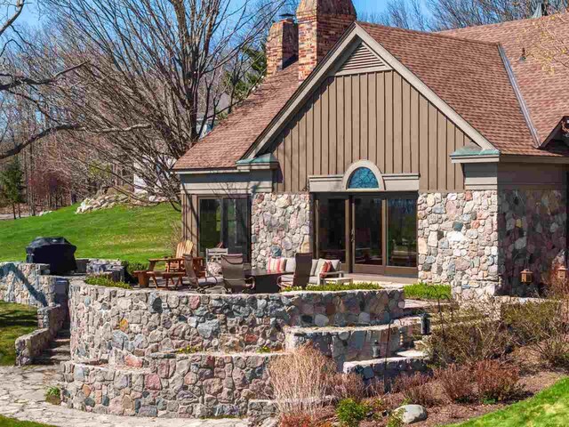 110 Birchwood Dr, Harbor Springs, MI 49740 - rear view of house with stone siding, roof with shingles, and a chimney