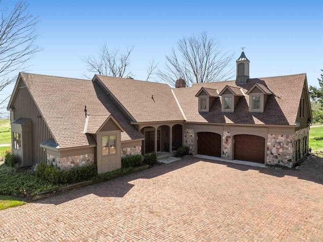 110 Birchwood Dr, Harbor Springs, MI 49740 - french country inspired facade featuring stone siding, decorative driveway, a chimney, and a garage