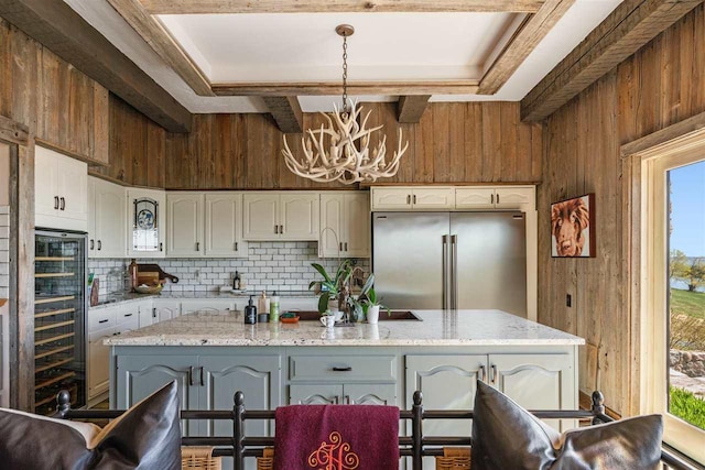 110 Birchwood Dr, Harbor Springs, MI 49740 - kitchen with high end refrigerator, wooden walls, a chandelier, white cabinetry, and beverage cooler