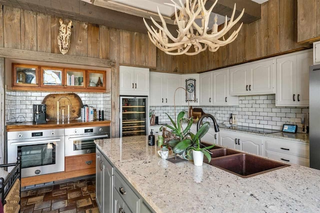 110 Birchwood Dr, Harbor Springs, MI 49740 - kitchen featuring appliances with stainless steel finishes, wine cooler, tasteful backsplash, and white cabinets