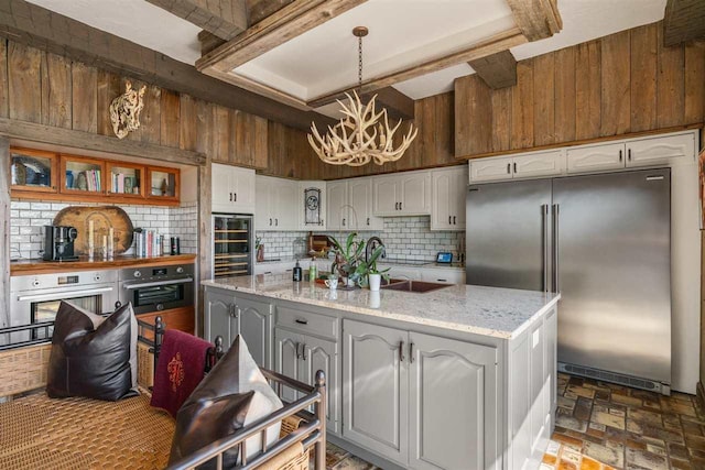 110 Birchwood Dr, Harbor Springs, MI 49740 - kitchen with stainless steel appliances, a chandelier, tasteful backsplash, white cabinetry, and wine cooler