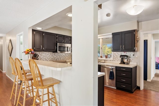 6141 S Old 31, Charlevoix, MI 49720 - kitchen with appliances with stainless steel finishes, a kitchen bar, wood finished floors, light countertops, and decorative backsplash