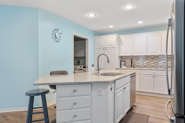 12175 Cottage Ln Unit 2, Charlevoix, MI 49720 - kitchen featuring stainless steel appliances, a sink, a breakfast bar area, white cabinetry, and light wood finished floors