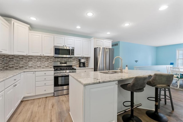 12175 Cottage Ln Unit 2, Charlevoix, MI 49720 - kitchen featuring stainless steel appliances, a sink, a kitchen island with sink, white cabinetry, and recessed lighting