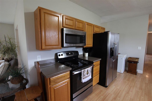 4155 Welsch Rd, Petoskey, MI 49770 - kitchen with stainless steel appliances, dark countertops, light wood-style flooring, and brown cabinets