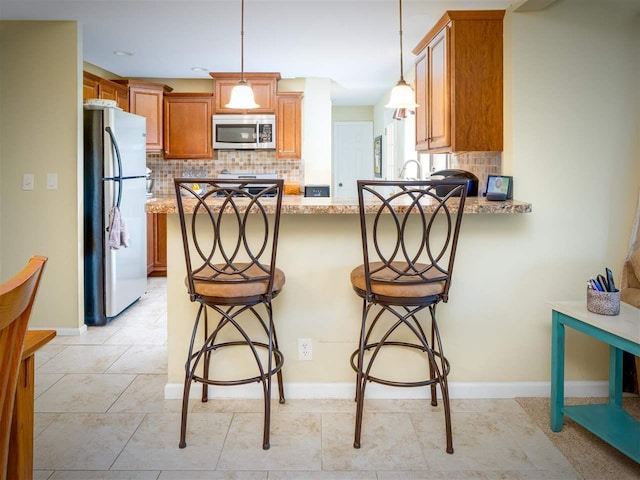 911 Regent Ct, Petoskey, MI 49770 - kitchen with appliances with stainless steel finishes, a peninsula, backsplash, and baseboards