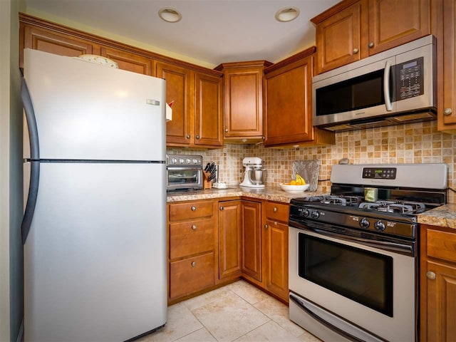 911 Regent Ct, Petoskey, MI 49770 - kitchen featuring stainless steel appliances, brown cabinets, tasteful backsplash, light tile patterned floors, and recessed lighting