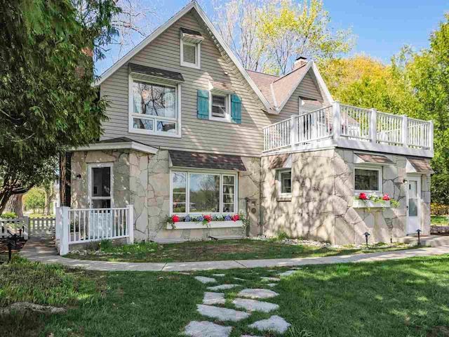 402 E Dixon Ave, Charlevoix, MI 49720 - rear view of property featuring a balcony, a chimney, a lawn, and stone siding