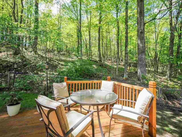 2729 Ranney Rd, East Jordan, MI 49727 - wooden terrace featuring outdoor dining area and a forest view