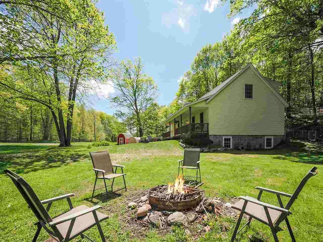 2729 Ranney Rd, East Jordan, MI 49727 - view of green lawn featuring an outdoor fire pit, a storage shed, and an outdoor structure