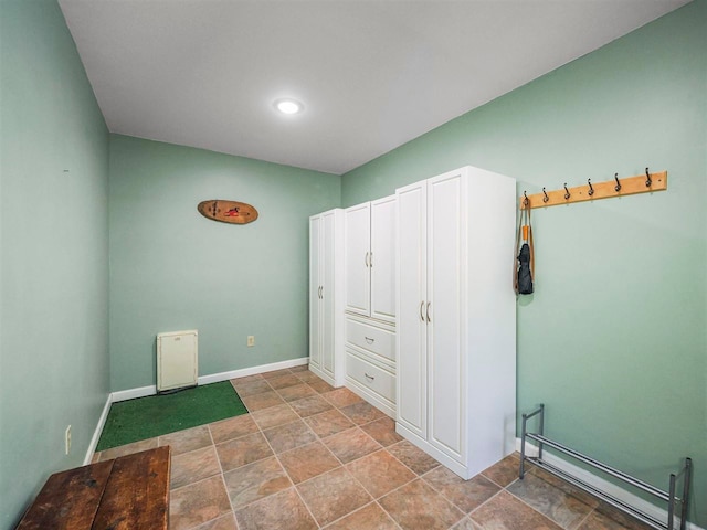 2729 Ranney Rd, East Jordan, MI 49727 - unfurnished bedroom with a baseboard heating unit, baseboards, and stone finish flooring