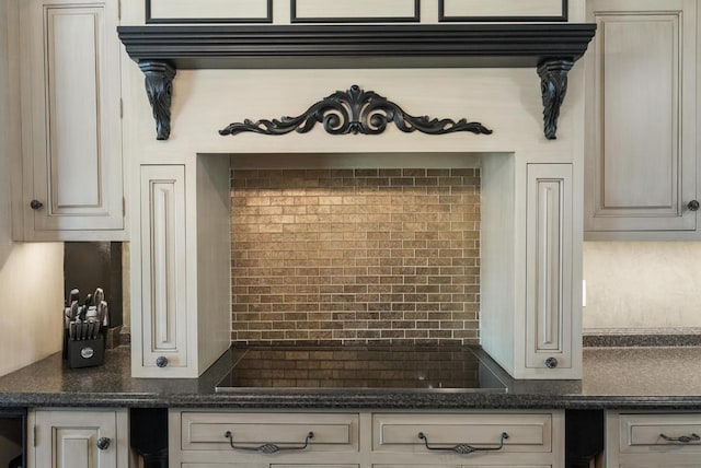 702 Michigan, Petoskey, MI 49770 - kitchen with black electric stovetop, backsplash, dark stone countertops, and cream cabinetry