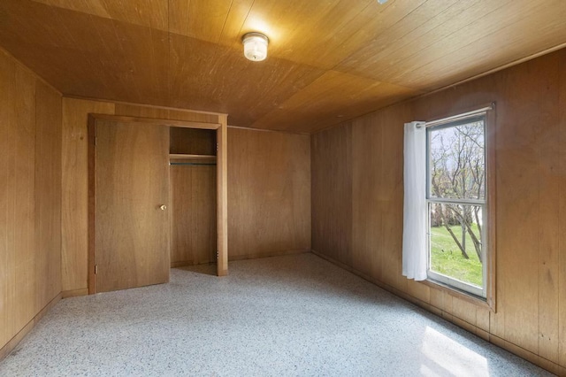 612 E Mitchell St, Petoskey, MI 49770 - unfurnished bedroom with wooden ceiling, multiple windows, wood walls, speckled floor, and a closet