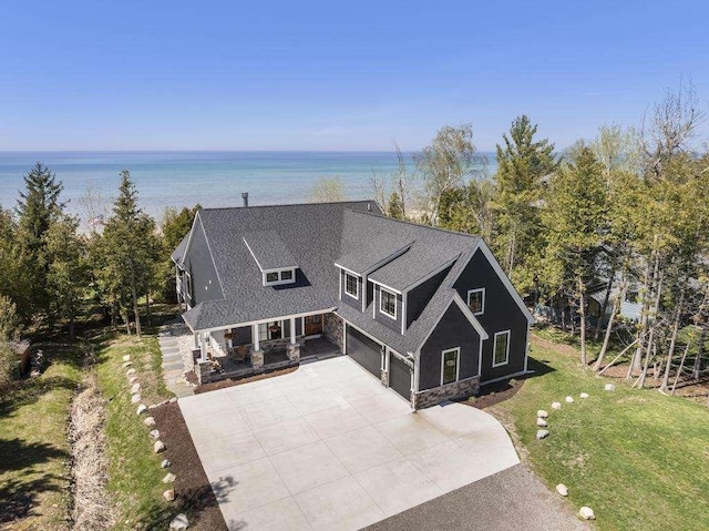 4435 Lake Shore Dr, Charlevoix, MI 49720 - view of front of home with a garage, driveway, a front yard, stone siding, and a shingled roof
