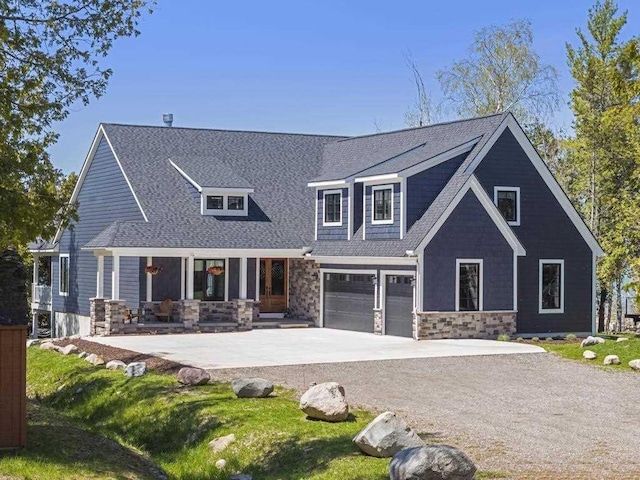 4435 Lake Shore Dr, Charlevoix, MI 49720 - view of front of house featuring stone siding, driveway, a porch, a garage, and roof with shingles