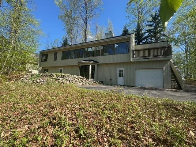 3237 Greenbriar, Harbor Springs, MI 49740 - back of house with a garage, driveway, a balcony, and a chimney