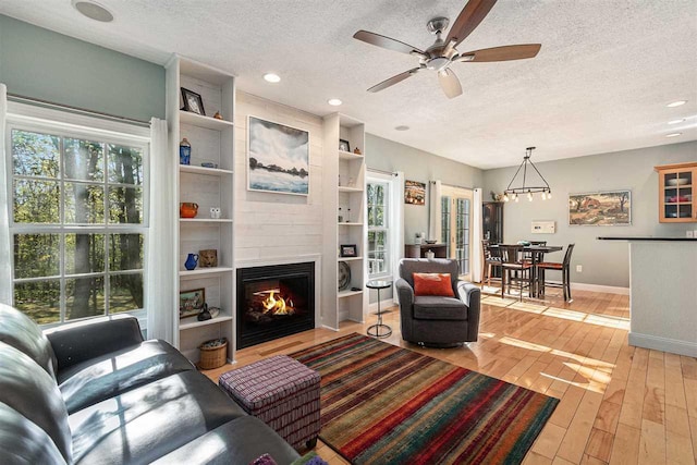 1766 Chippewa Bch, Indian River, MI 49749 - living area featuring a textured ceiling, light wood-style flooring, ceiling fan, a large fireplace, and recessed lighting