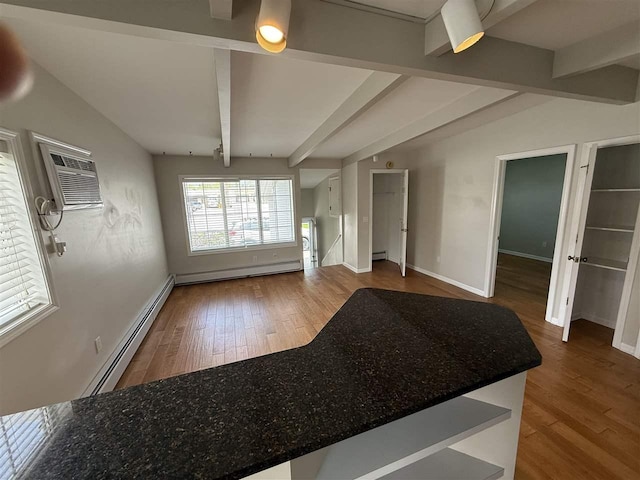 13456-7 Stover Rd Unit 7, Charlevoix, MI 49720 - unfurnished living room featuring a baseboard heating unit, beam ceiling, wood finished floors, and baseboards