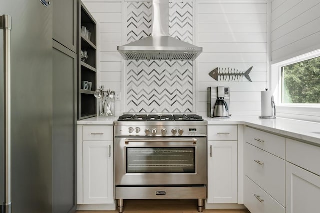 2018 Greenbriar Ter, Harbor Springs, MI 49740 - kitchen featuring high end stove, wall chimney exhaust hood, tasteful backsplash, open shelves, and white cabinetry