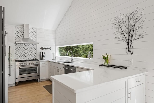 2018 Greenbriar Ter, Harbor Springs, MI 49740 - kitchen featuring wall chimney range hood, stainless steel appliances, a sink, vaulted ceiling, and a peninsula