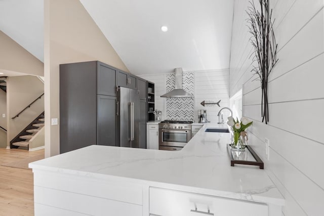 2018 Greenbriar Ter, Harbor Springs, MI 49740 - kitchen featuring wall chimney exhaust hood, premium appliances, a sink, light stone counters, and lofted ceiling
