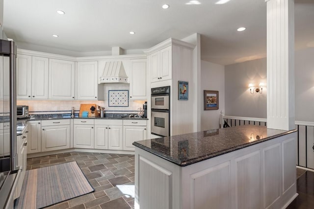 4064 Harborview Rdg Unit 17, Bay Harbor, MI 49770 - kitchen with stainless steel double oven, backsplash, custom exhaust hood, dark stone finish flooring, and a wainscoted wall