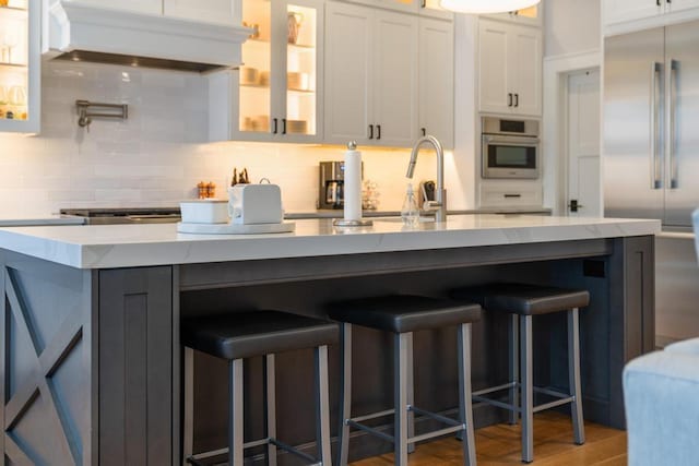 917 Grove St, Petoskey, MI 49770 - kitchen featuring premium range hood, stainless steel appliances, decorative backsplash, glass insert cabinets, and white cabinets