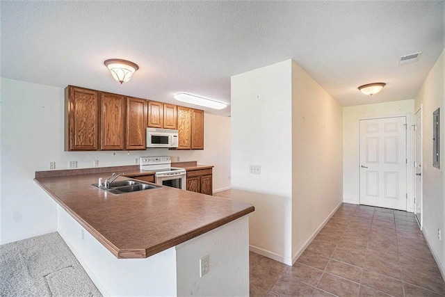 1556 Emerald Ct Unit 89, Petoskey, MI 49770 - kitchen with white appliances, a sink, brown cabinets, a peninsula, and baseboards
