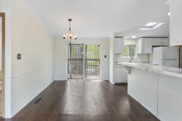 7245-83 Upper Kelsey Dr, Charlevoix, MI 49720 - kitchen featuring white appliances, a chandelier, dark wood-style floors, white cabinets, and a sink