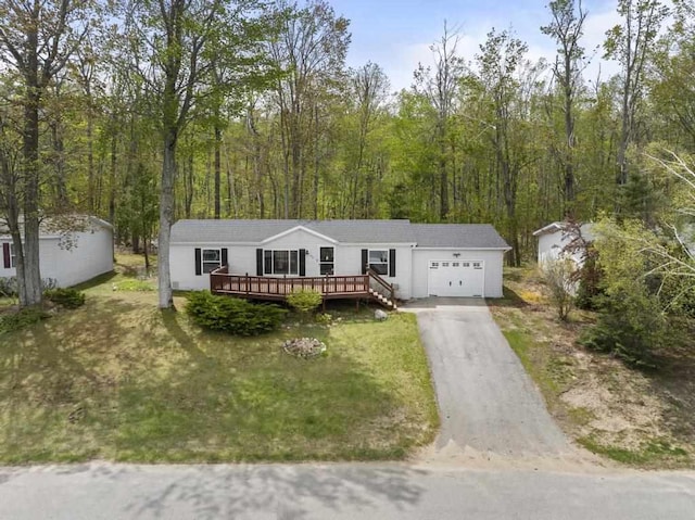7245-83 Upper Kelsey Dr, Charlevoix, MI 49720 - manufactured / mobile home with a garage, asphalt driveway, a wooden deck, a front lawn, and a wooded view