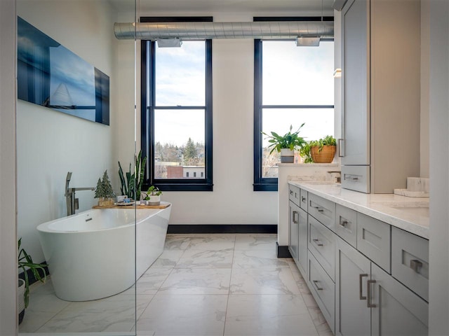 422 E Mitchell Unit 1, Petoskey, MI 49770 - full bathroom with marble look tile flooring, a freestanding tub, double vanity, and baseboards