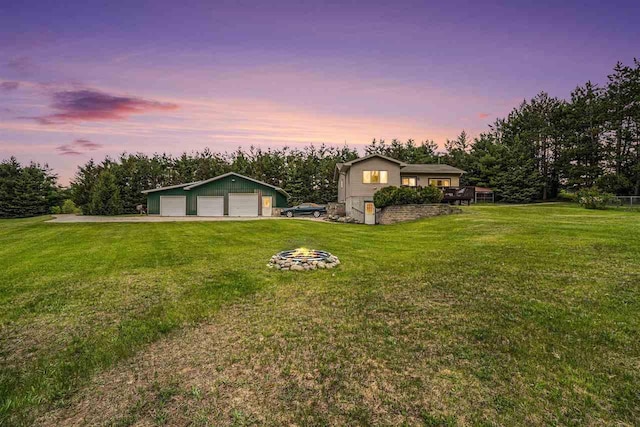 4024 Behling, Boyne City, MI 49712 - yard at dusk with a garage, a lawn, an outdoor structure, and a fire pit