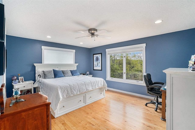 9030 Sugar Tree Ln, Charlevoix, MI 49720 - bedroom with wood finished floors, an office area, a textured ceiling, baseboards, and ceiling fan