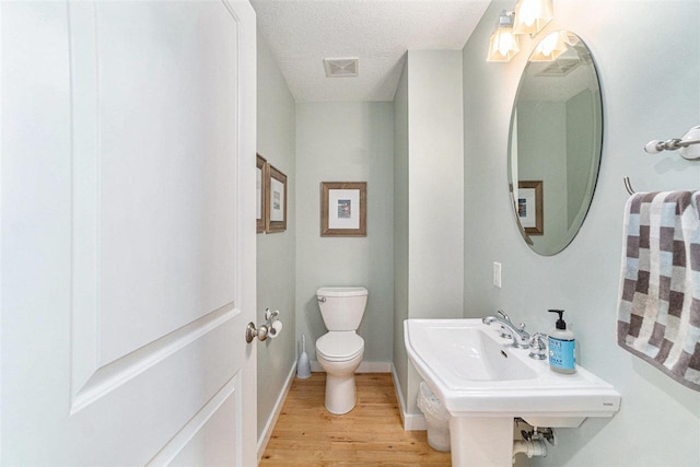 9030 Sugar Tree Ln, Charlevoix, MI 49720 - bathroom featuring toilet, wood finished floors, baseboards, and a textured ceiling