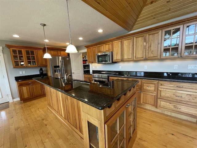 9030 Sugar Tree Ln, Charlevoix, MI 49720 - kitchen featuring stainless steel appliances, brown cabinets, a kitchen island with sink, light wood-type flooring, and recessed lighting