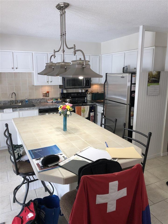 915 Robinson St Unit 2, Boyne City, MI 49712 - kitchen featuring appliances with stainless steel finishes, white cabinets, tile counters, tasteful backsplash, and a sink