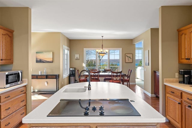 8530 Dustin Ln, East Jordan, MI 49727 - kitchen featuring stainless steel microwave, a sink, light countertops, black electric stovetop, and a chandelier