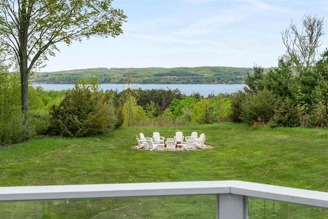 8530 Dustin Ln, East Jordan, MI 49727 - view of grassy yard featuring an outdoor fire pit, a water view, and a wooded view