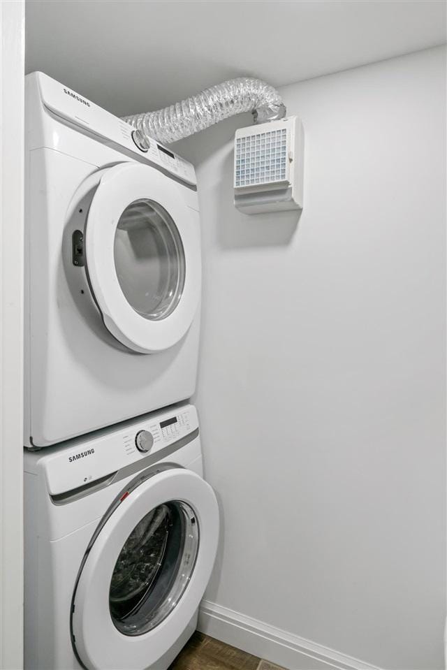8530 Dustin Ln, East Jordan, MI 49727 - washroom with stacked washing machine and dryer, baseboards, and wood finished floors