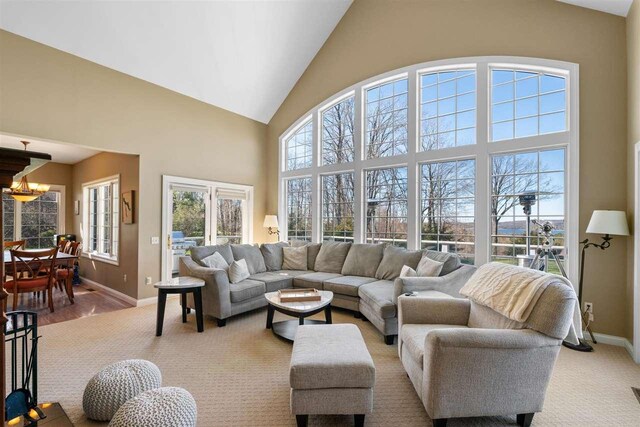 8530 Dustin Ln, East Jordan, MI 49727 - living area featuring baseboards, high vaulted ceiling, and light carpet