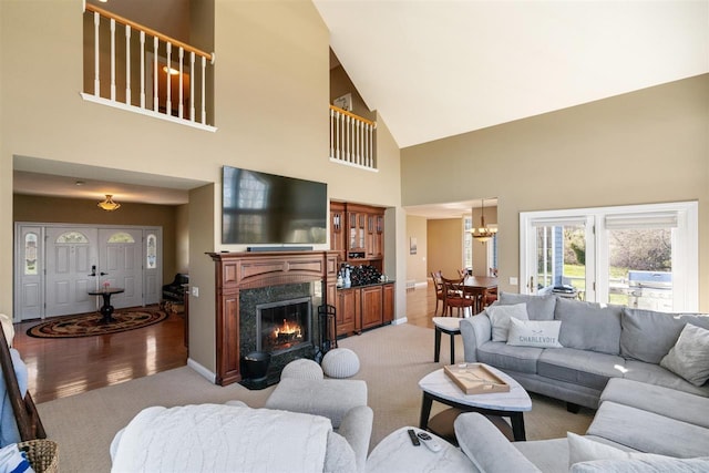 8530 Dustin Ln, East Jordan, MI 49727 - living room with light colored carpet, high vaulted ceiling, a chandelier, baseboards, and a premium fireplace